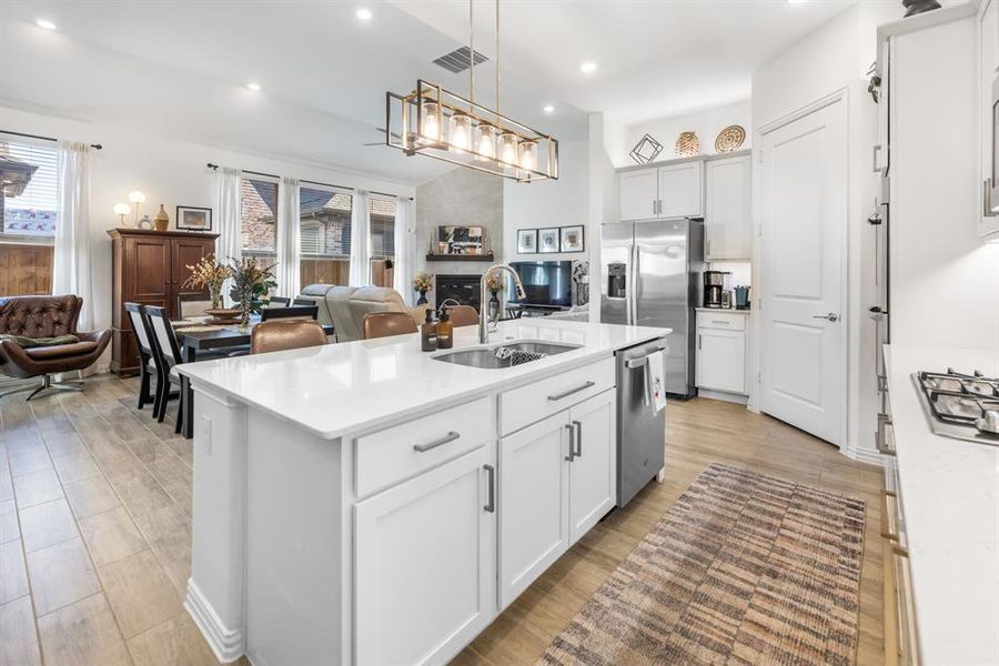 Kitchen with open floor plan, a kitchen island with sink, light stone counters, recessed lighting, and white cabinetry Kitchen with open floor plan, a kitchen island with sink, light stone counters, recessed lighting, and white cabinetry