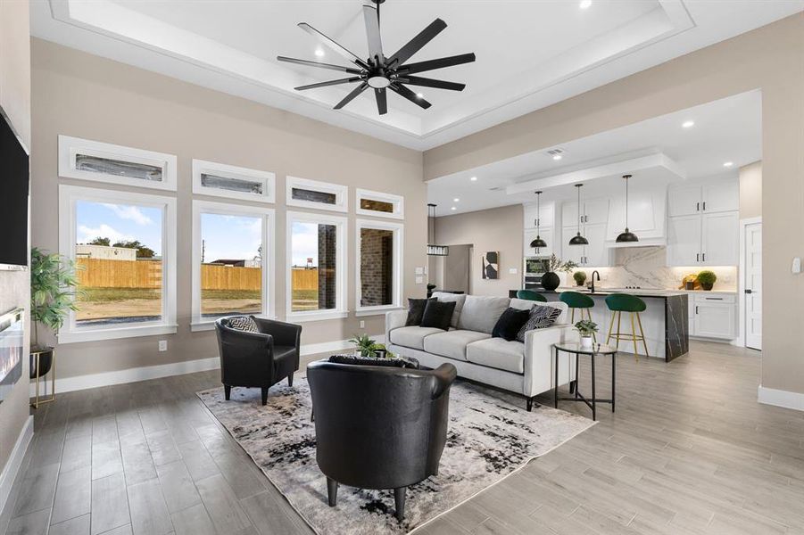 Living room featuring a tray ceiling, light hardwood / wood-style flooring, and ceiling fan