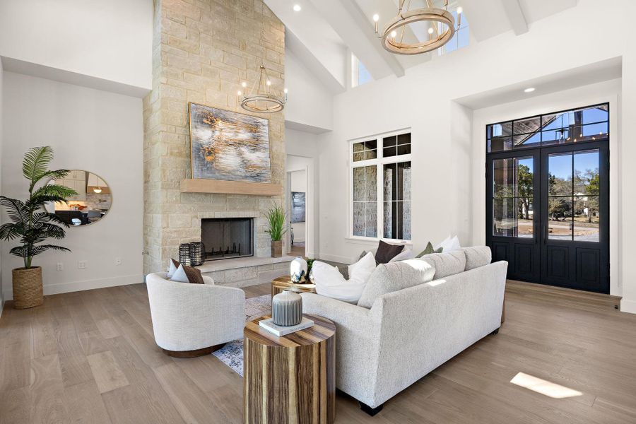 Living room with beam ceiling, a fireplace, wood finished floors, high vaulted ceiling, and baseboards