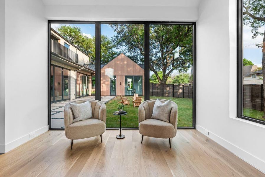 Floor-to-ceiling windows frame the backyard, creating a peaceful sitting area with uninterrupted views of the outdoor setting.