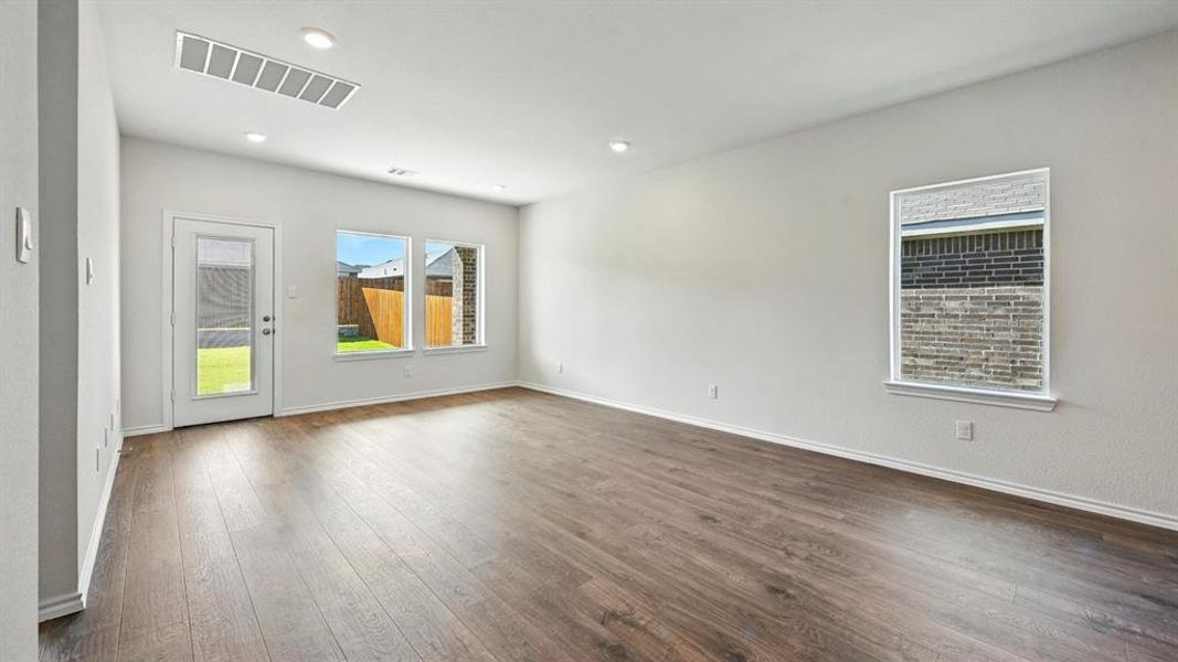 Spacious room featuring wood-finish flooring, white walls, and recessed lighting