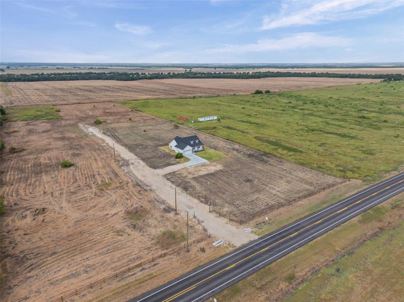 An aerial perspective showcases a countryside residence surrounded by expansive acreage.