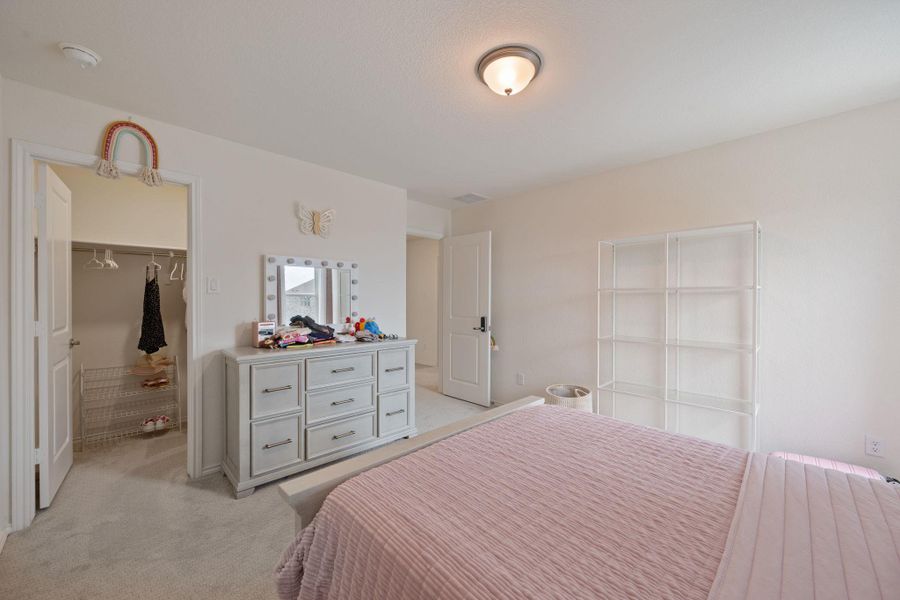 Bedroom featuring a walk in closet and light colored carpet