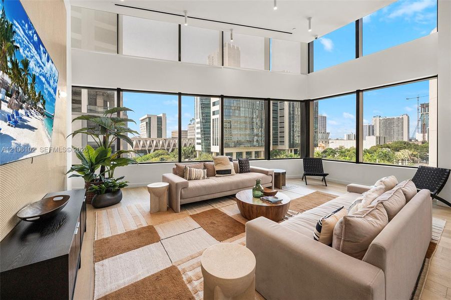 Floor-to-ceiling windows, double-height ceilings, recessed track lighting, and wide-plank wood-finish flooring
