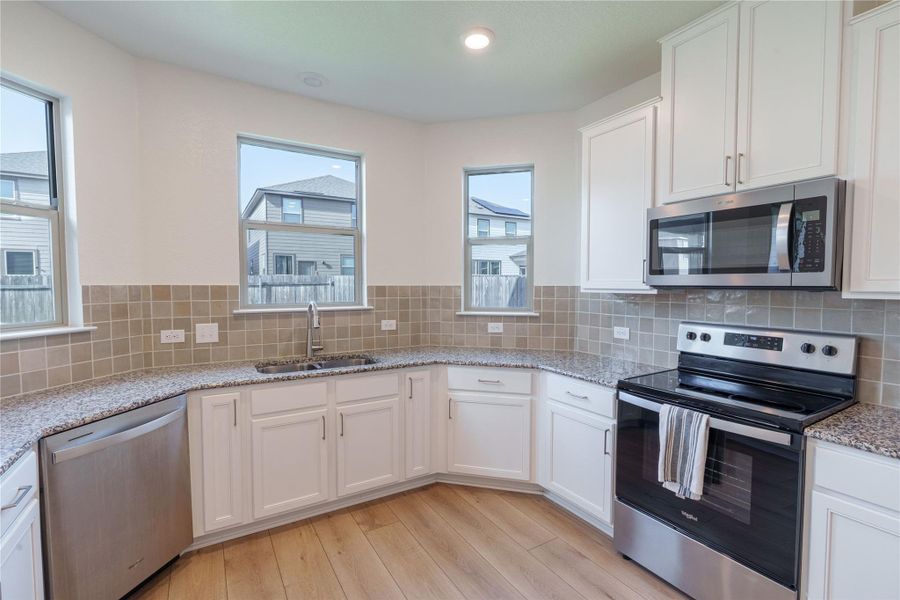 Granite counters and stainless steel appliances outfit this contemporary L-shaped kitchen. Granite counters and stainless steel appliances outfit this contemporary L-shaped kitchen.