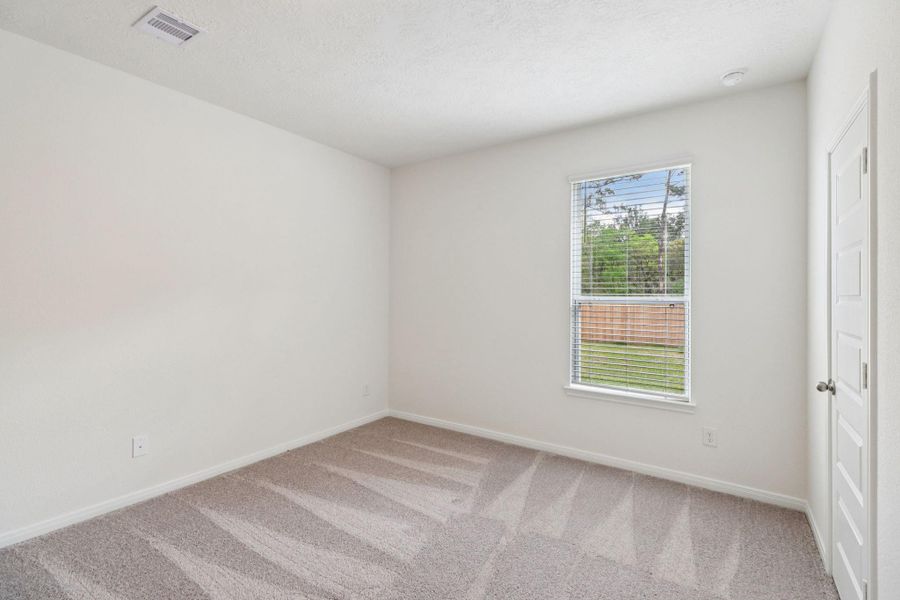 This secondary bedroom offers comfort and style with plush carpeting, neutral paint tones, recessed lighting, a large window with blinds, and a generously sized closet.