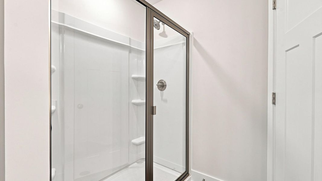 Sophisticated primary bathroom with a spacious walk-in shower and polished hardware by DRB Homes Sophisticated primary bathroom with a spacious walk-in shower and polished hardware by DRB Homes