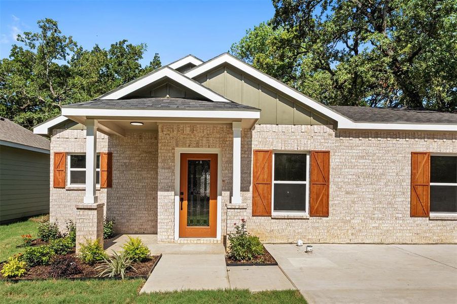 Light brick exterior with a prominent wooden entry door featuring glass inserts Light brick exterior with a prominent wooden entry door featuring glass inserts