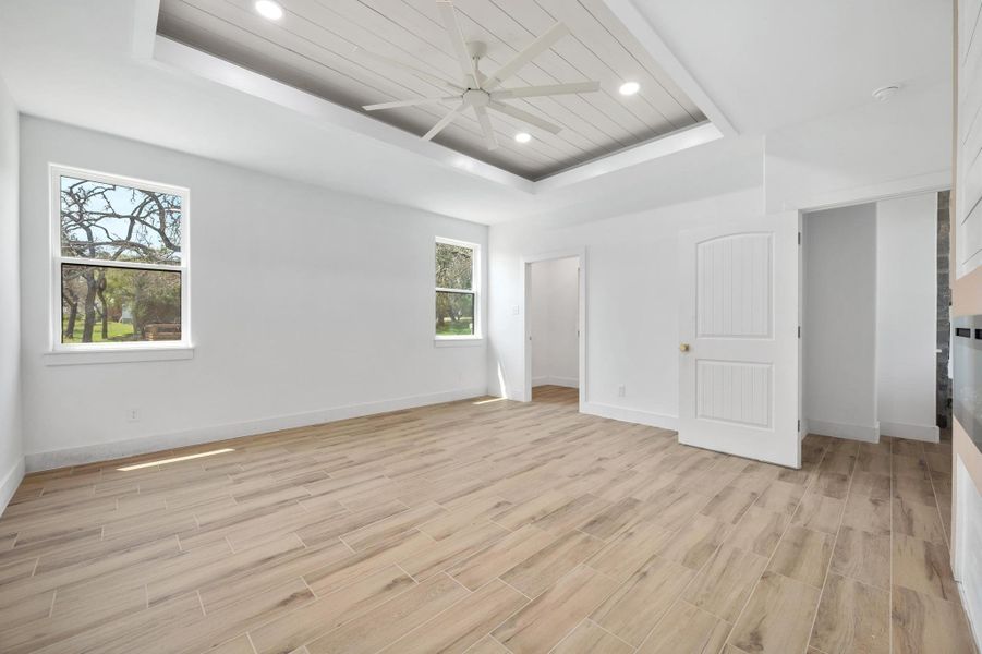 Bedroom with a tray ceiling, recessed lighting, wood finish floors, wood ceiling, and ceiling fan Bedroom with a tray ceiling, recessed lighting, wood finish floors, wood ceiling, and ceiling fan