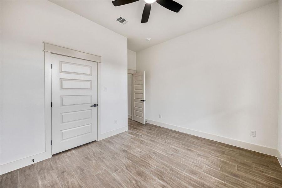 Unfurnished bedroom with wood finish floors, a closet, and a ceiling fan