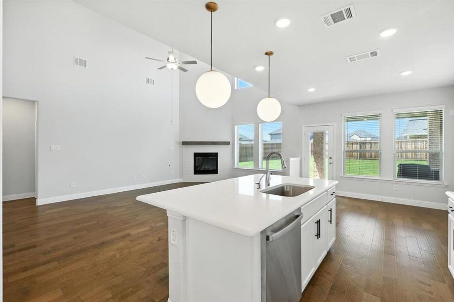Stylish and sleek kitchen with modern lighting, wood floors, white cabinets and light countertops with gas cooktop and SS appliances.