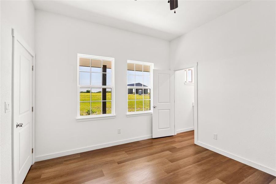 Room featuring wood-finish flooring, white walls, and two double-hung windows with white frames