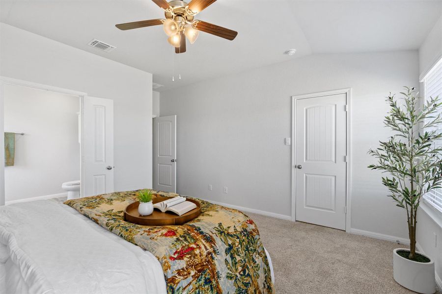Bedroom with light carpet, a ceiling fan, vaulted ceiling, and connected bathroom