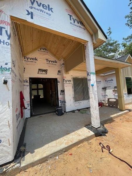 FRONT PORCH IS WELCOMING WITH CEDAR COLUMNS AND CEILING, STAMPED CONCRETE  AND CUSTOM BUILT METAL DOUBLE  FRONT DOORS.