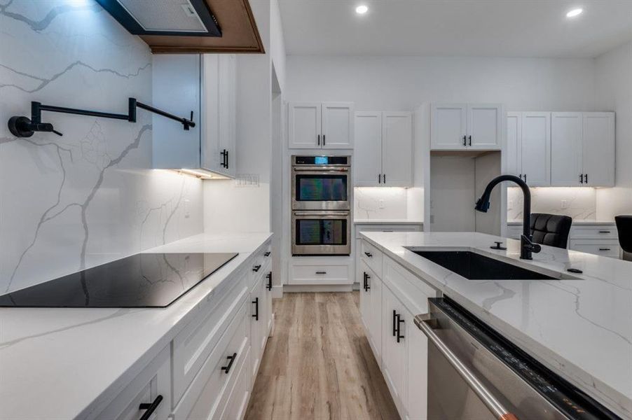 Chef-inspired wraparound kitchen showcasing two oversized islands with seating for nine, double ovens, pot filler, massive statement vent hood, and a fully equipped pantry with electrical outlets for added convenience. Chef-inspired wraparound kitchen showcasing two oversized islands with seating for nine, double ovens, pot filler, massive statement vent hood, and a fully equipped pantry with electrical outlets for added convenience.