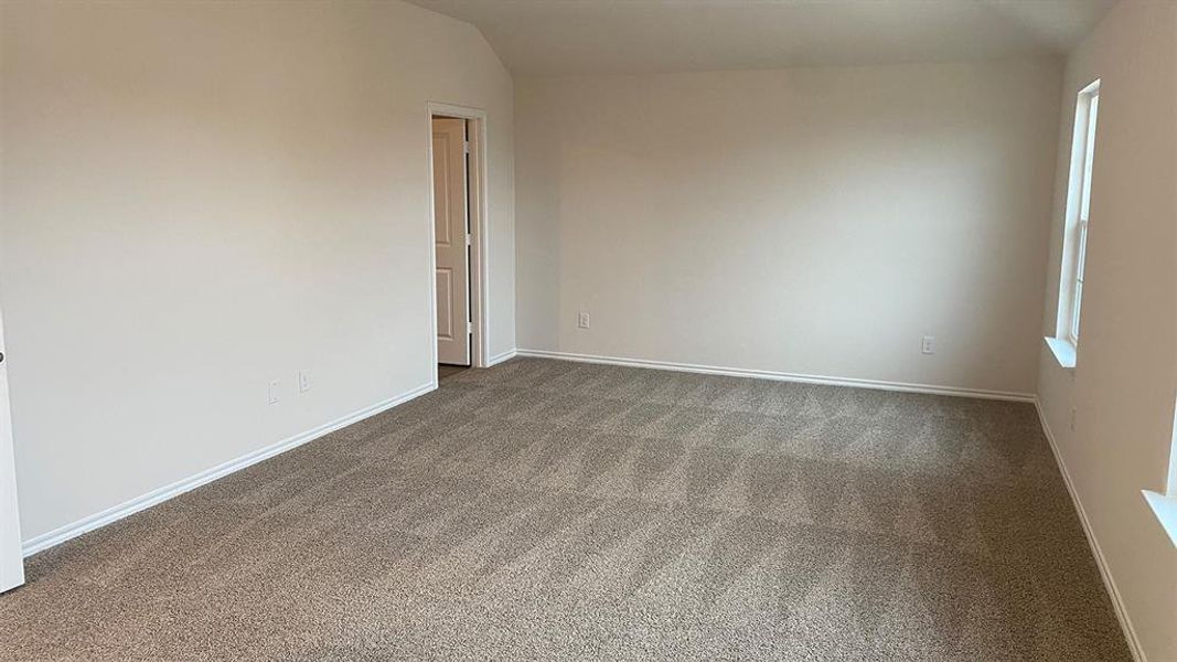 Empty room featuring vaulted ceiling and dark colored carpet