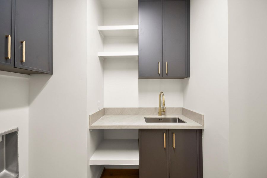 A well-appointed and functional laundry room designed for everyday convenience, featuring ample countertop space for folding, custom cabinetry for organized storage, and a clean, modern aesthetic.