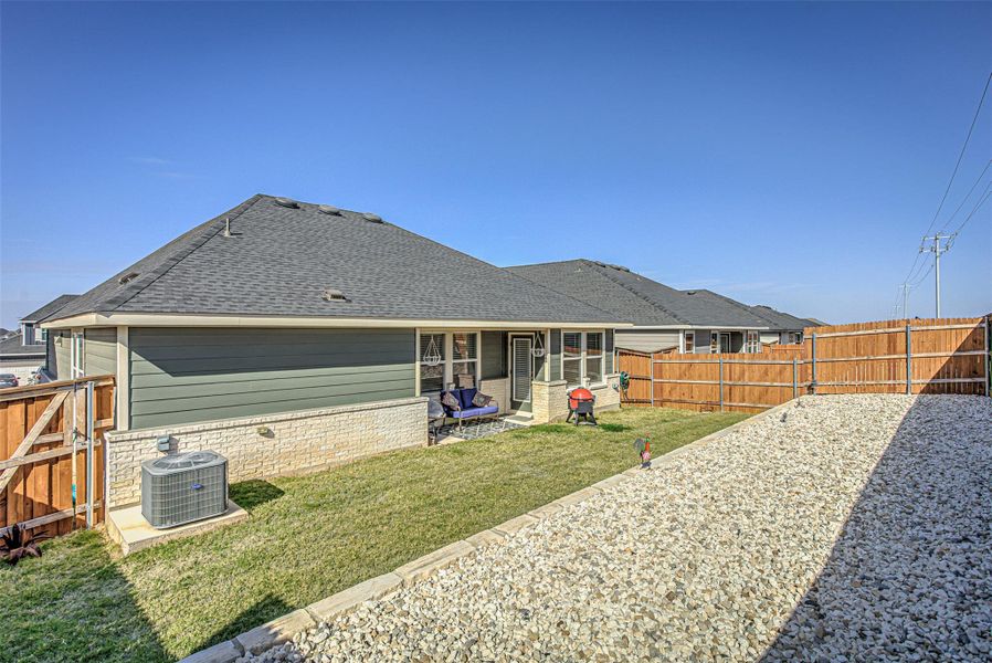 Rear view of property featuring a fenced backyard, a sunroom, a shingled roof, and a gate