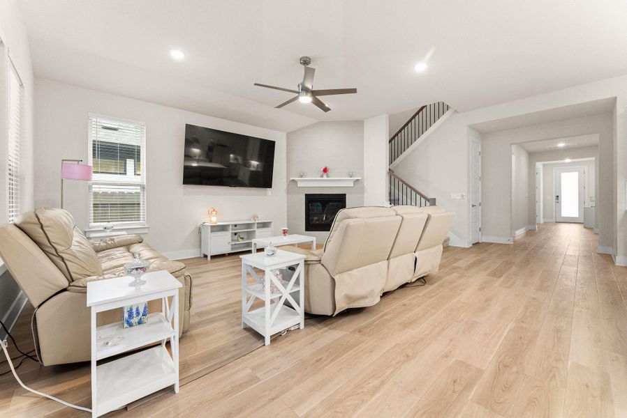 The spacious family room features a corner gas fireplace with mantle, ceiling fan with light, recessed lighting, and two-inch blinds.