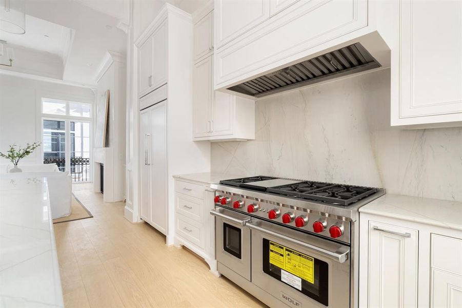 The gourmet kitchen features Energy Star Certified Wolf gourmet appliances including 24" Wolf Microwave, 24" Asko Dishwasher, and this stunning 48" 8-Burner Gas Cooktop (Griddle Optional). (photo of interior model home with smaller floor plan)