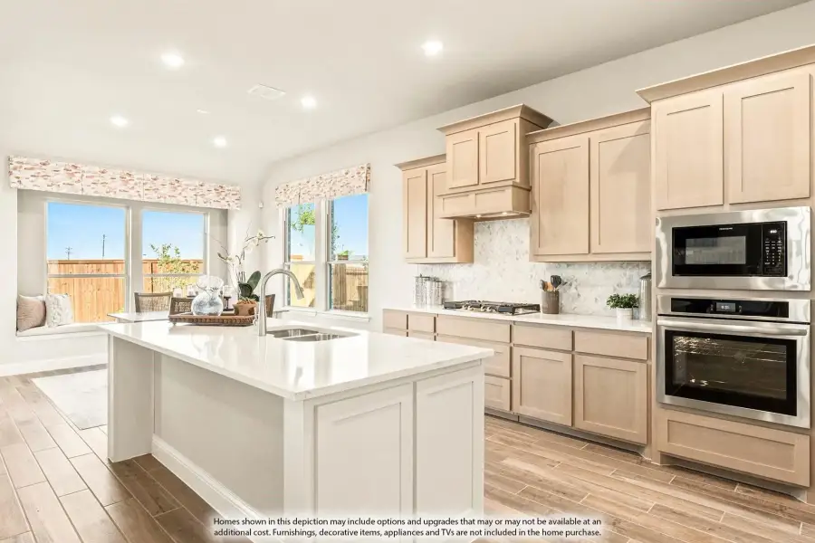 Kitchen with light wood cabinets, center island with sink, stainless steel appliances, and tile backsplash