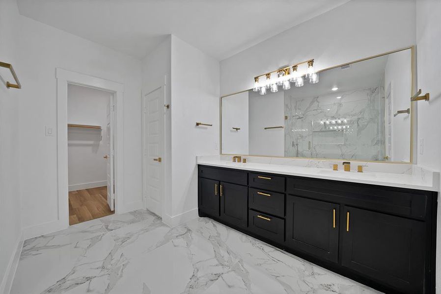 Bathroom with double vanity, a marble finish shower, a walk in closet, and light marble finish flooring