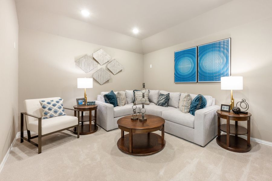 Living room with gray sectional sofa, round wood coffee table, accent chair, and blue wall art on beige carpet