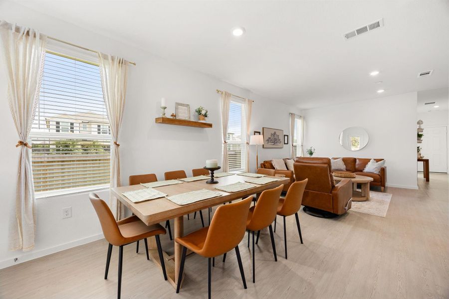 The seamless flow between the dining room and living room creates a spacious, connected atmosphere while maintaining defined spaces for relaxing and entertaining.