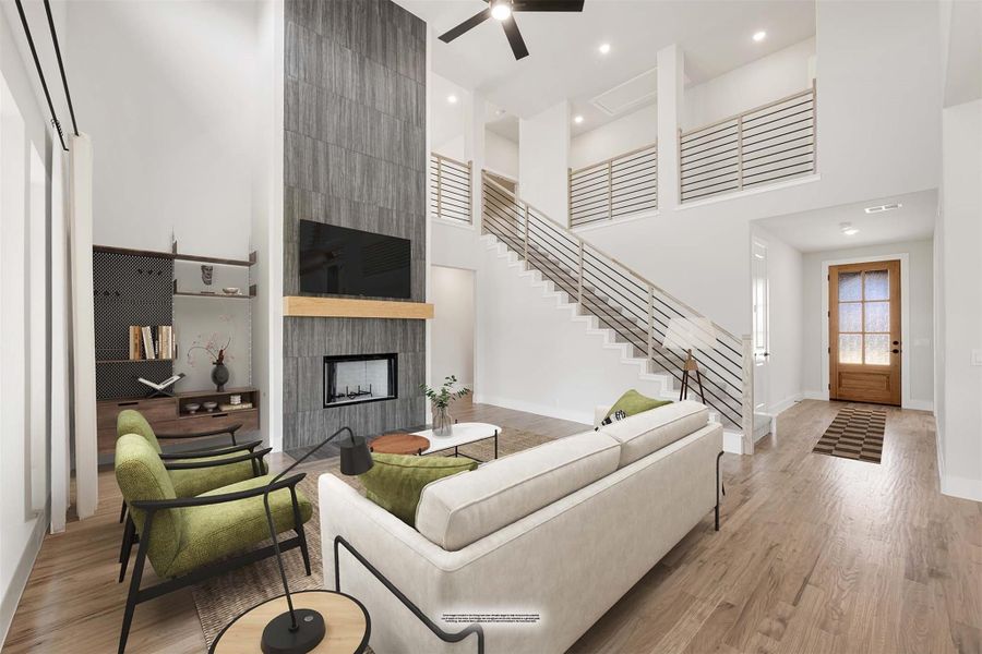 Open living room with two-story ceiling, floor-to-ceiling tile fireplace, staircase, and hardwood floors
