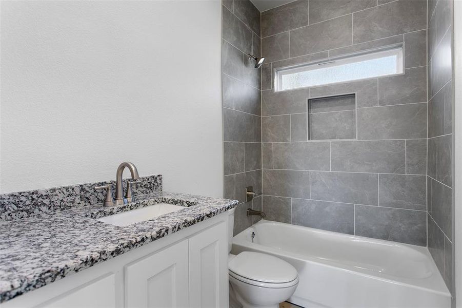 Full bathroom featuring toilet, vanity, and tiled shower / bath