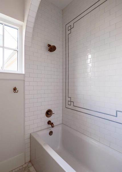 Bath tub with subway tile arch and inlay design.