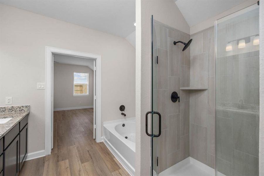 This en-suite bathroom is the epitome of modern luxury. It features a separate tub and shower combination for the ultimate in comfort and convenience. The sleek vanity and mirror provide a stylish focal point, and the thoughtfully designed layout adds to the luxurious feel of this private retreat.