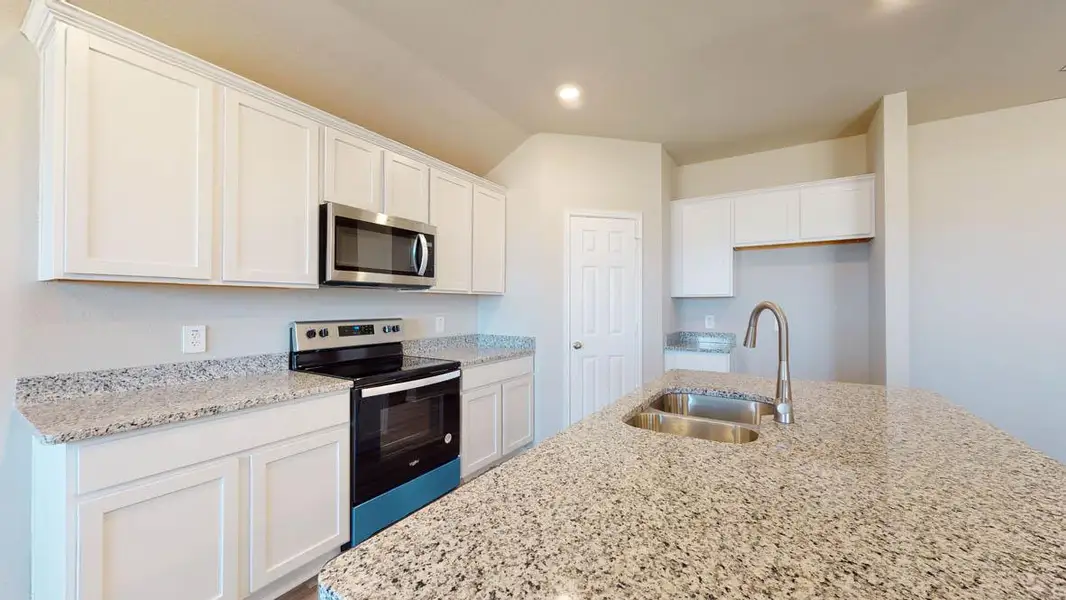 Kitchen featuring stainless steel appliances, white cabinetry, light stone counters, an island with sink, and recessed lighting
