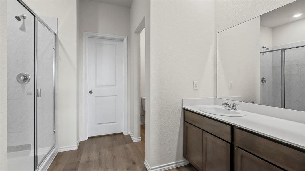 Full bathroom with a shower stall, vanity, dark wood finished floors, and a textured wall