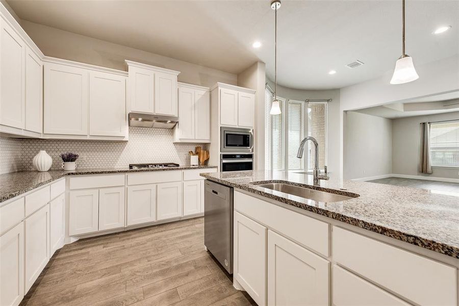Kitchen with white cabinetry, plenty of natural light, light wood-style floors, pendant lighting, and recessed lighting