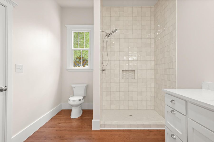 A well-lit bathroom showcases a spacious walk-in shower with sleek tiling and rich hardwood flooring. A well-lit bathroom showcases a spacious walk-in shower with sleek tiling and rich hardwood flooring.