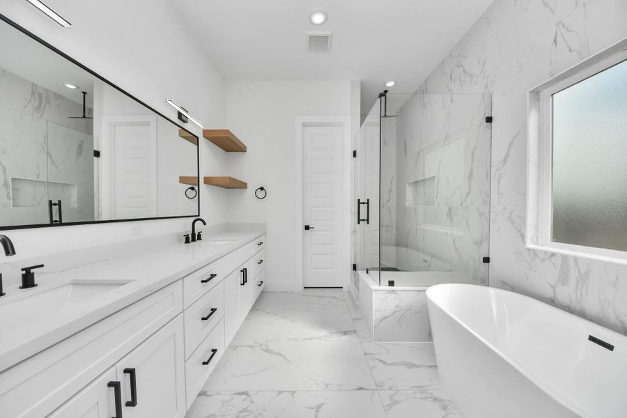 This bathroom features a modern, elegant design with marble-patterned tiles, a glass-enclosed shower, a freestanding bathtub, and a double vanity with sleek black fixtures. The room is bright and spacious, with ample natural light from a large frosted window.