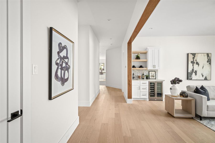 Stylish upstairs landing with custom built in wet bar featuring quartz counters, floating wood shelves, and wine storage. The warm wood accents and modern design create an inviting transition between the upstairs living spaces. Stylish upstairs landing with custom built in wet bar featuring quartz counters, floating wood shelves, and wine storage. The warm wood accents and modern design create an inviting transition between the upstairs living spaces.