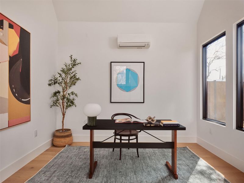 Office area featuring light wood-style flooring and vaulted ceiling