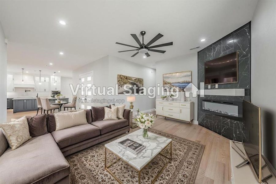 Living room with light wood-type flooring, ceiling fan, recessed lighting, and a fireplace