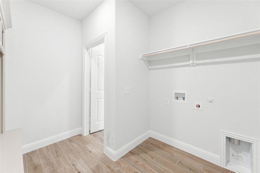 Laundry room with wood-look tile floors, wall-mounted shelf, and washer and dryer hookups Laundry room with wood-look tile floors, wall-mounted shelf, and washer and dryer hookups