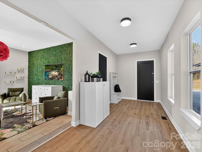 Bright, spacious hallway with warm wood flooring, clean modern lines, and natural light streaming in from large windows.