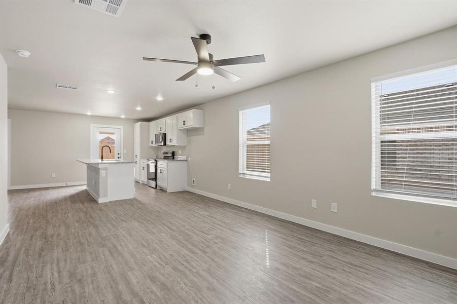 Unfurnished living room featuring light wood-type flooring, a ceiling fan, and recessed lighting