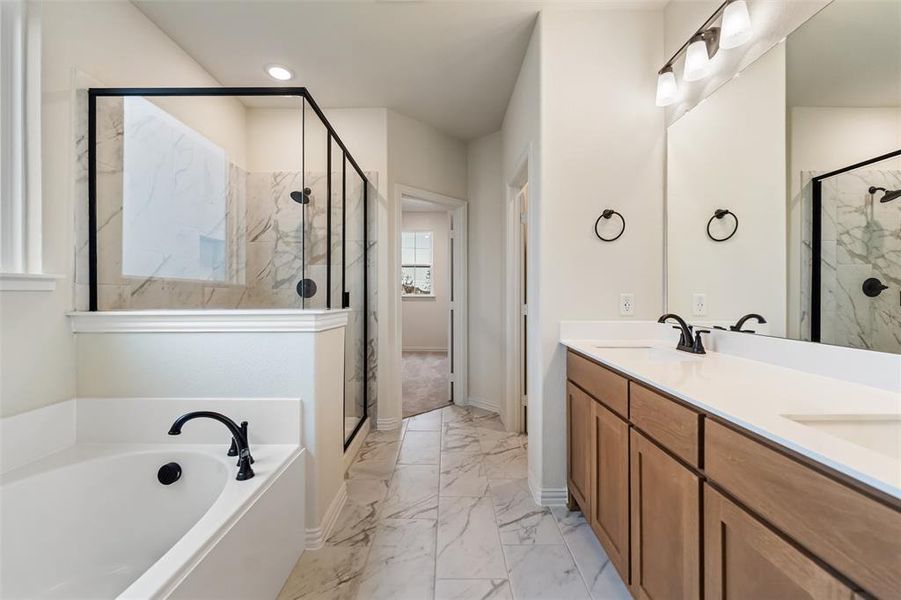 Full bath featuring double vanity, a marble finish shower, light marble finish flooring, and a garden tub