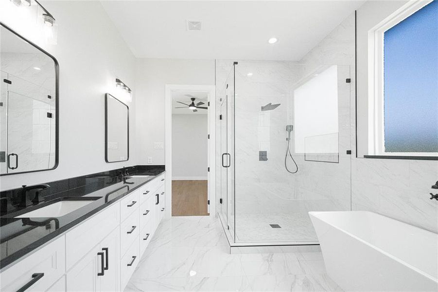 Full bathroom with double vanity, a marble finish shower, a freestanding bath, recessed lighting, and light marble finish flooring