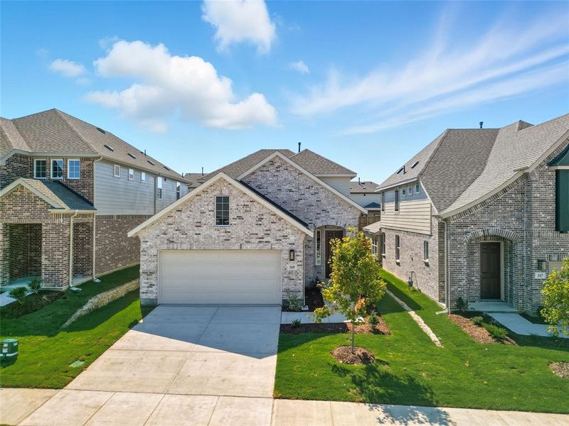 French country home with driveway, a front yard, an attached garage, roof with shingles, and brick siding French country home with driveway, a front yard, an attached garage, roof with shingles, and brick siding