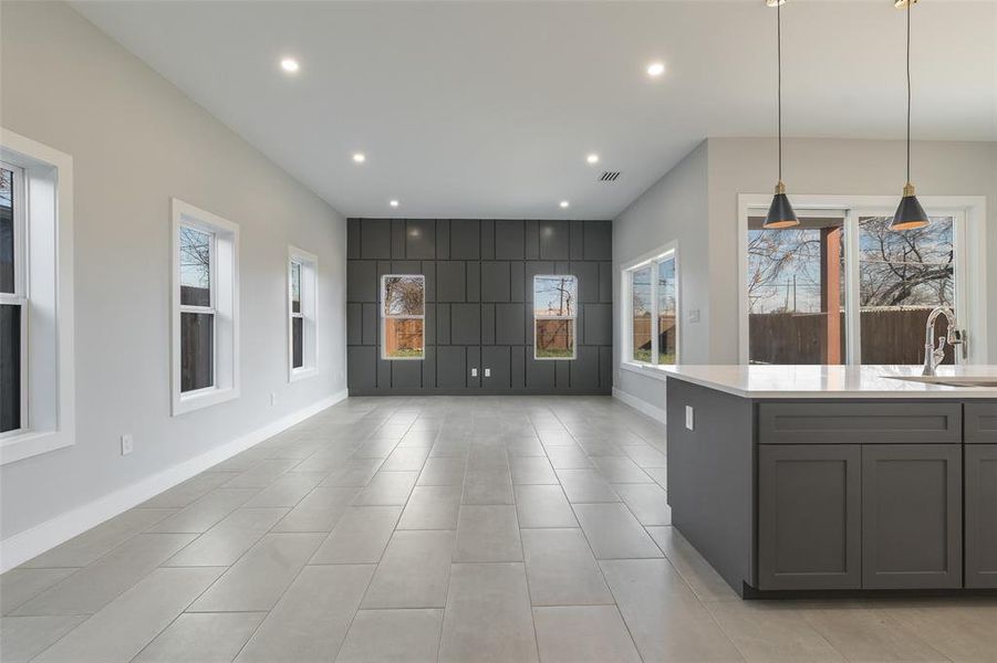 Kitchen with hanging light fixtures, light tile patterned flooring, gray cabinetry, and sink