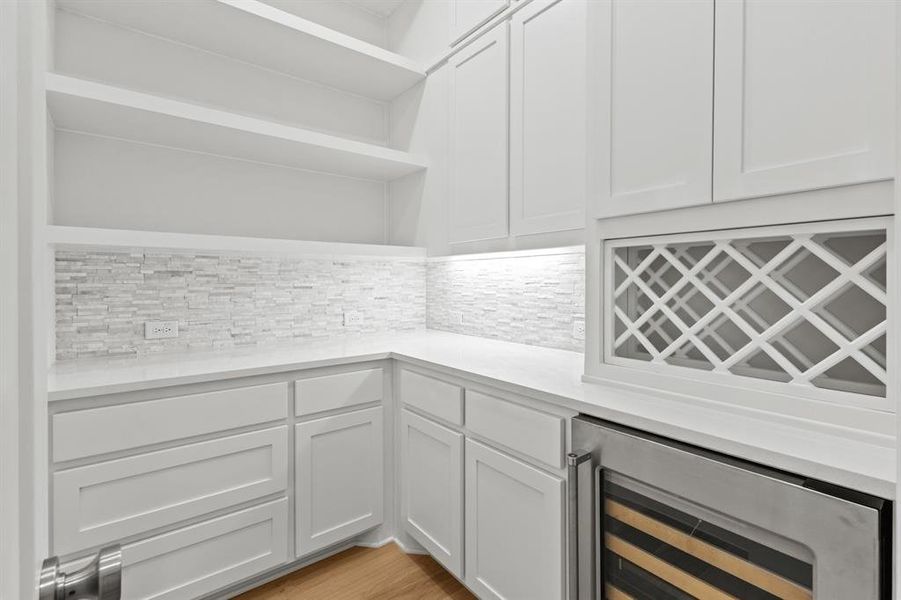 Bar featuring open shelves, wine cooler, white cabinets, backsplash, and light stone counters