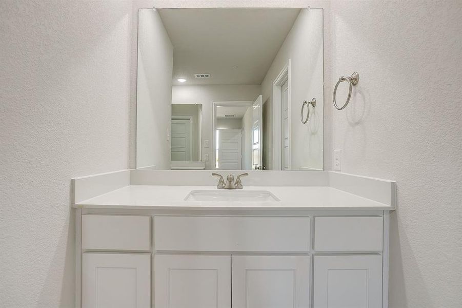 Bathroom featuring a textured wall and vanity