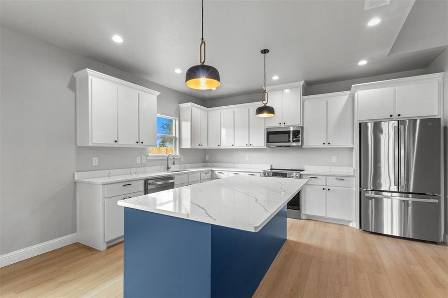 Kitchen with stainless steel appliances, a center island, decorative light fixtures, white cabinetry, and recessed lighting